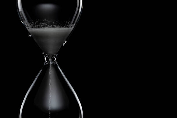 istock Close up of hourglass on black background. 1180911982