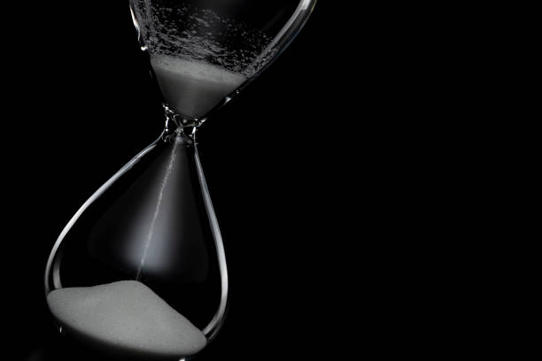 istock Close up of hourglass on black background. 1180912020