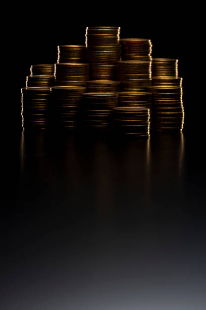 istock Pile of coins stacked on black background 1180912042