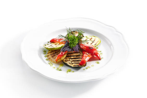 istock White Restaurant Plate of Grilled Vegetables and Fresh Greens Isolated 1180912370