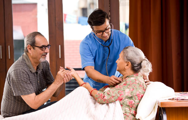 istock Home caregiver examining senior woman using stethoscope on bed 1180917285
