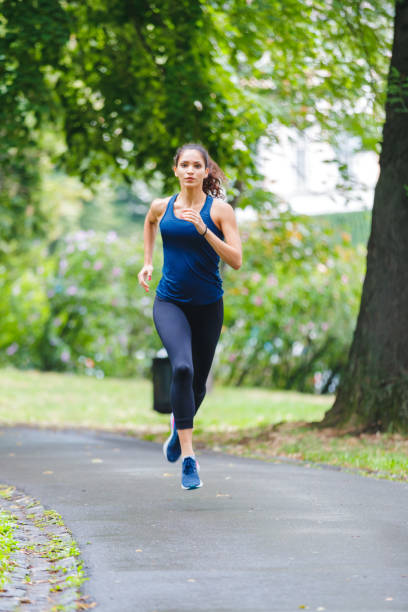 istock Young woman jogging in the park 1180918200