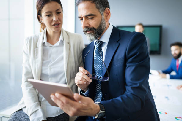 istock Happy business colleagues in modern office using tablet 1180923584