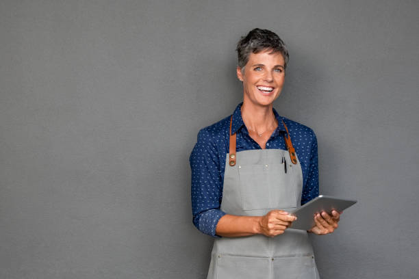 istock Mature woman in apron holding digital tablet 1180925093