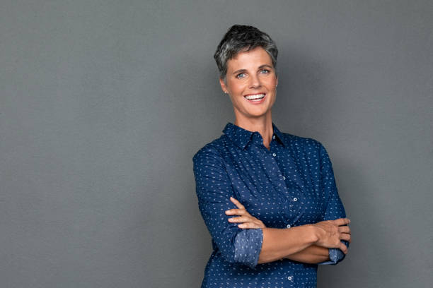 Happy mature woman laughing on grey wall