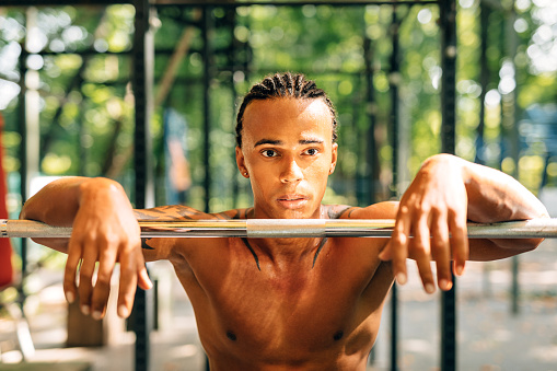 Portrait of a young sportsman resting during exercises leaning on a weight bar