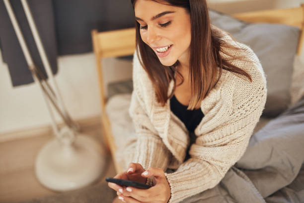 istock Woman sitting on bed in bedroom and using smart phone. 1180925292