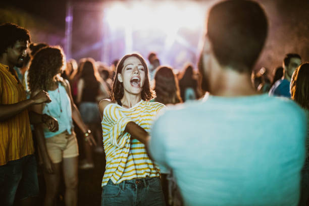 젊은 부부는 밤에 음악 콘서트에서 춤을 추고 노래합니다. - popular music concert performance outdoors crowd 뉴스 사진 이미지