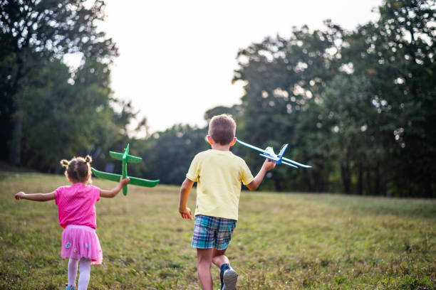 istock Kids playing with airplane toy in field 1180928764