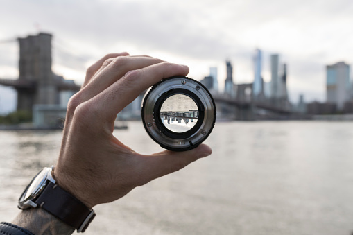 Hand holding a lens against New York City skyline