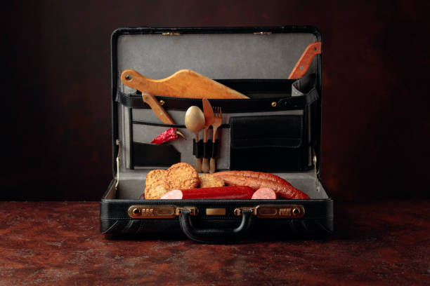 istock Black leather case with sausage, cutlets and cutlery on brown table. 1180930133
