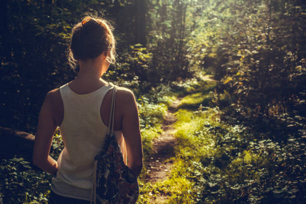 istock Woman walking alone in the forest 1180931367