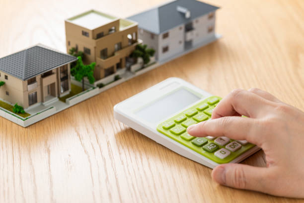 istock Man and house model calculating with calculator 1180931385