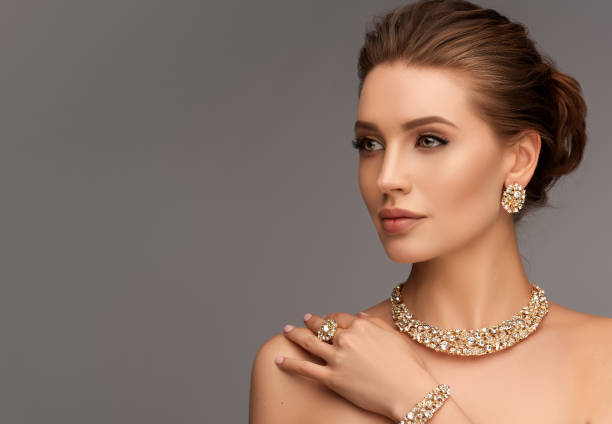 Alluring woman dressed in a posh jewelry set of necklace, ring and earrings. Elegant evening style. Portrait of alluring woman dressed in a posh jewelry set of necklace, ring and earrings. Pretty model is gazing at the viewer by magnetic look, perfect evening makeup and hair gathered in elegant bun. female likeness photos stock pictures, royalty-free photos & images