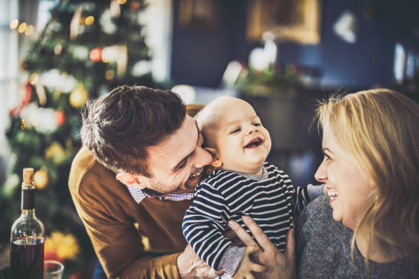 Young happy parents having fun with their baby son during New Year at home. Young happy parents having fun with their baby boy on New Year's day. baby new years eve new years day new year stock pictures, royalty-free photos & images