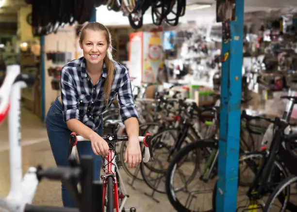 Portrait of female is standing with bicycle in store