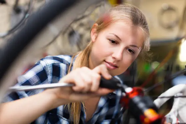 Portrait of girl who is fixing her bicycle indoors