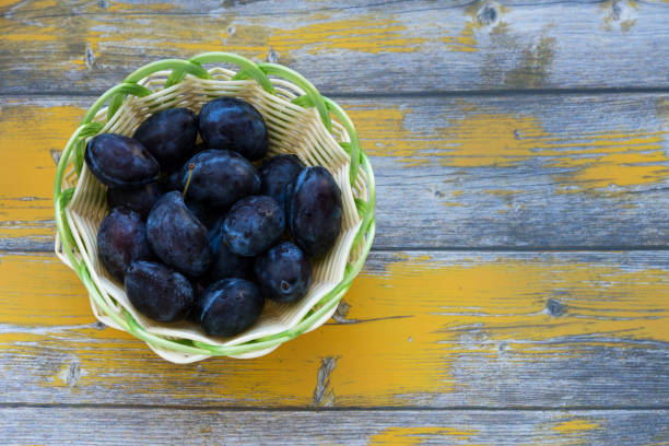istock Ripe plums on a wooden background 1180932749