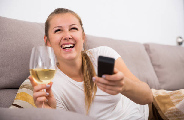 istock Girl is resting with wine and watching TV 1180937195