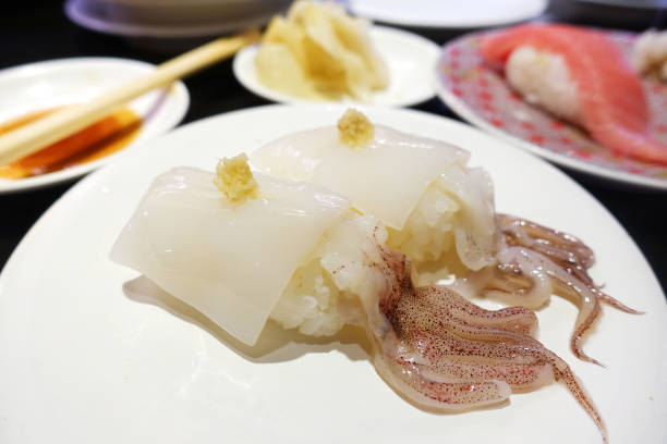 Japanese raw squid nigiri with ginger on a white plate