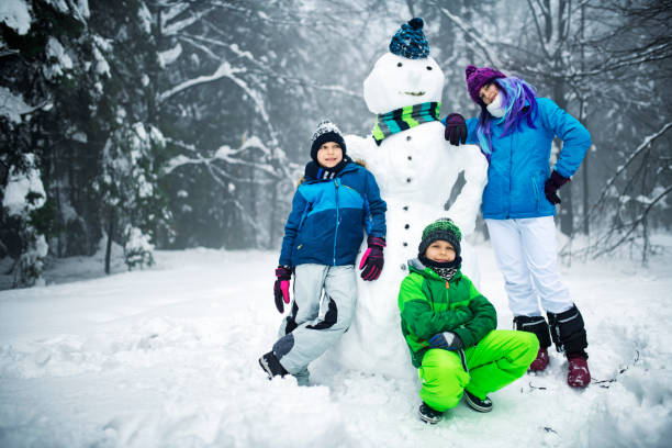 Thee kids have built a snowman. \nNikon D850