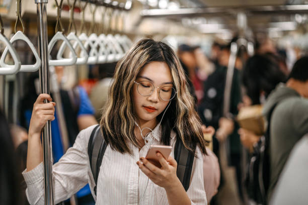 Texting to her friend on her way to school in subway Young female student standing in subway train and text messaging on mobile phone taiwan people stock pictures, royalty-free photos & images