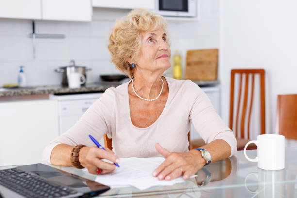 istock Senior woman filling up documents 1180941966