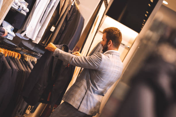 istock Young man choosing suit in clothes store. 1180942139