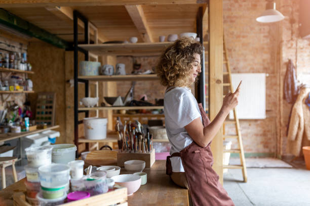 istock Female potter with smartphone in art studio 1180949515