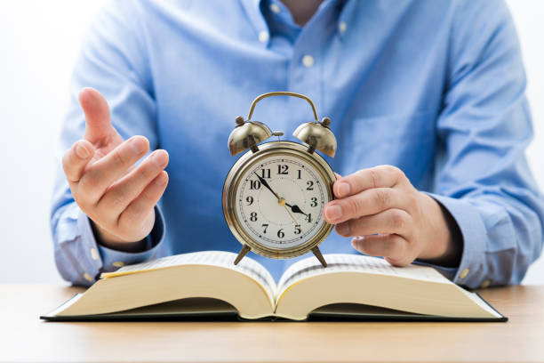istock Open book and alarm clock. Sitting man. 1180951085