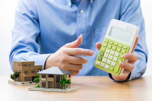 istock House model on the table. Man with calculator in hand. 1180951781
