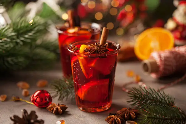 Christmas mulled wine with fruits and spices in glass on a wooden  background. Traditional hot drink at Christmas or Autumn time