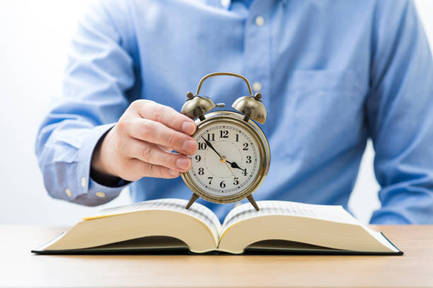 istock Open book and alarm clock. Sitting man. 1180951826