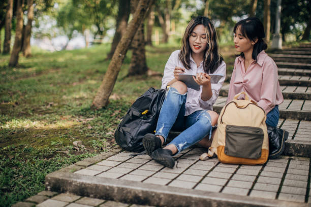 istock Young ladies students studying together in park 1180951978