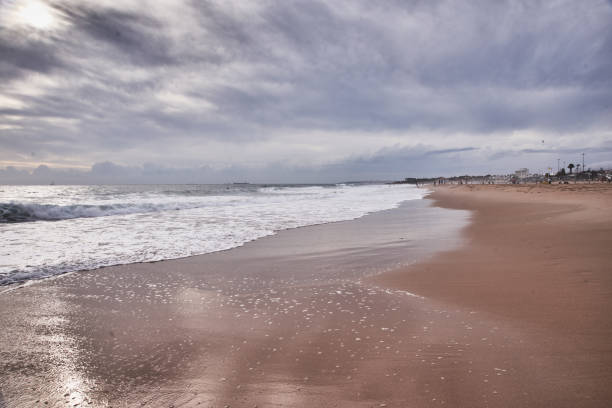 istock Amazing sunset view to Atlantic ocean waves and long yellow sand Carcavelos Beach. 1180954158