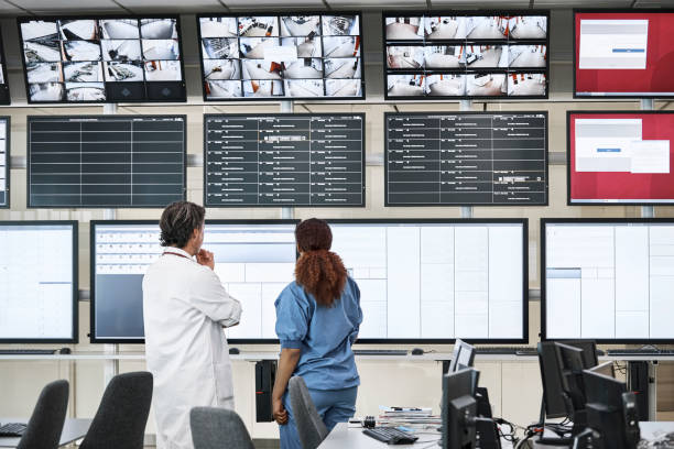médecins discutant au-dessus des écrans dans la salle de contrôle - salle de contrôle photos et images de collection