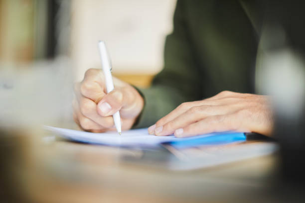 istock Close up of hands signing a document. 1180956114