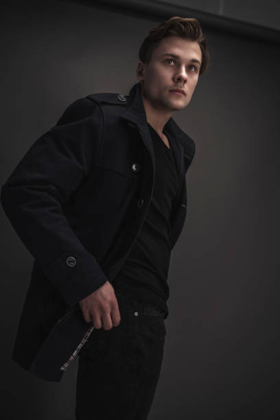 istock Young stylish man posing on a gray background. Wearing a black coat. Model test. 1180956466