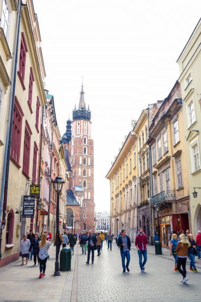 turisti in via florianska con la chiesa della basilica di santa maria sullo sfondo, la strada più famosa di cracovia, polonia - florianska street foto e immagini stock