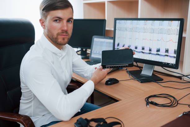 istock Digital device. Polygraph examiner works in the office with his lie detector's equipment 1180956859