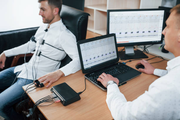 istock Do you remember when you first time saw that safe. Suspicious man passes lie detector in the office. Asking questions. Polygraph test 1180957564