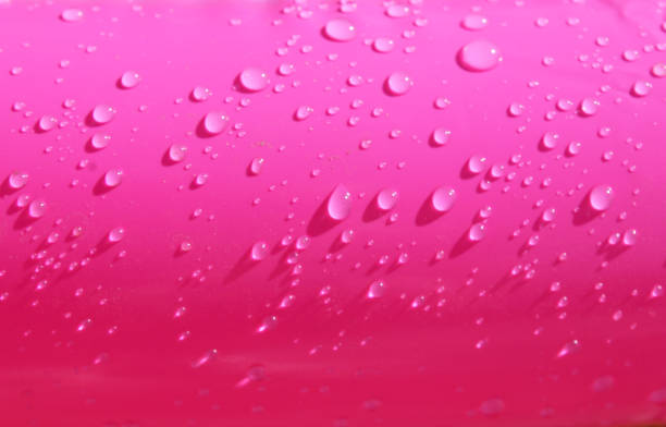 Bright pink inflatable paddling pool surface with water drops on it. Summer picture of swimming pool