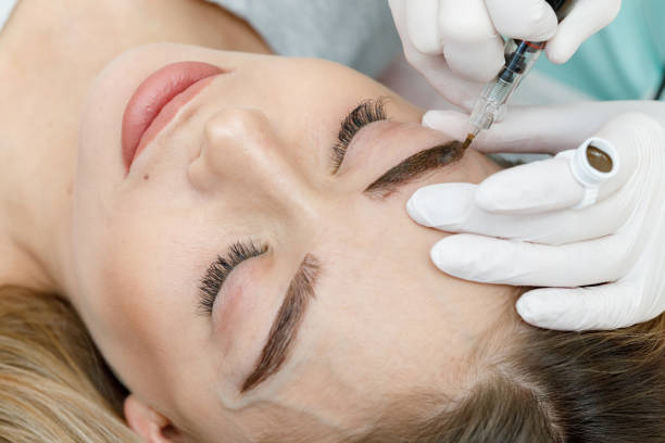 istock Permanent makeup, tattooing of eyebrows. Cosmetologist applying make up 1180960656