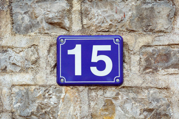istock Blue house number fifteen on a stone wall background 1180960659