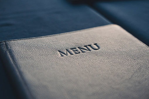 Libro de menú azul oscuro sobre la mesa en el restaurante, enfoque selectivo photo