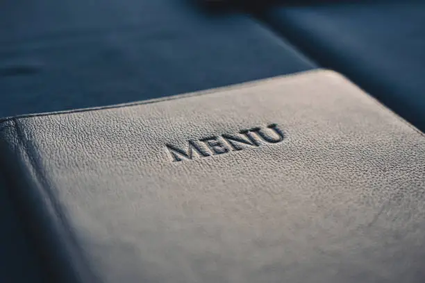 Photo of Dark blue menu book on table in restaurant, selective focus