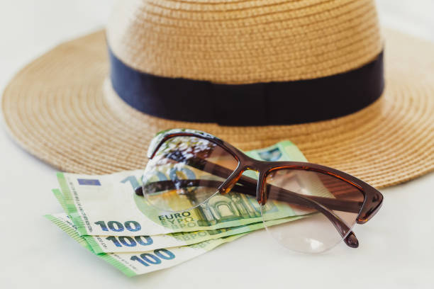 istock Sun hat with sunglasses and 100 hundredth euro banknotes. Vacation concept 1180960719