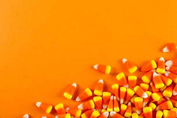 istock Bright colorful candy corn scattered on textured surface as symbol of autumnal holidays. 1180960742