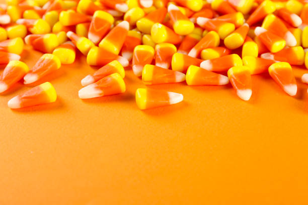 istock Bright colorful candy corn scattered on textured surface as symbol of autumnal holidays. 1180960757
