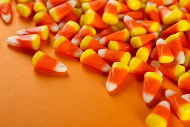 istock Bright colorful candy corn scattered on textured surface as symbol of autumnal holidays. 1180960861